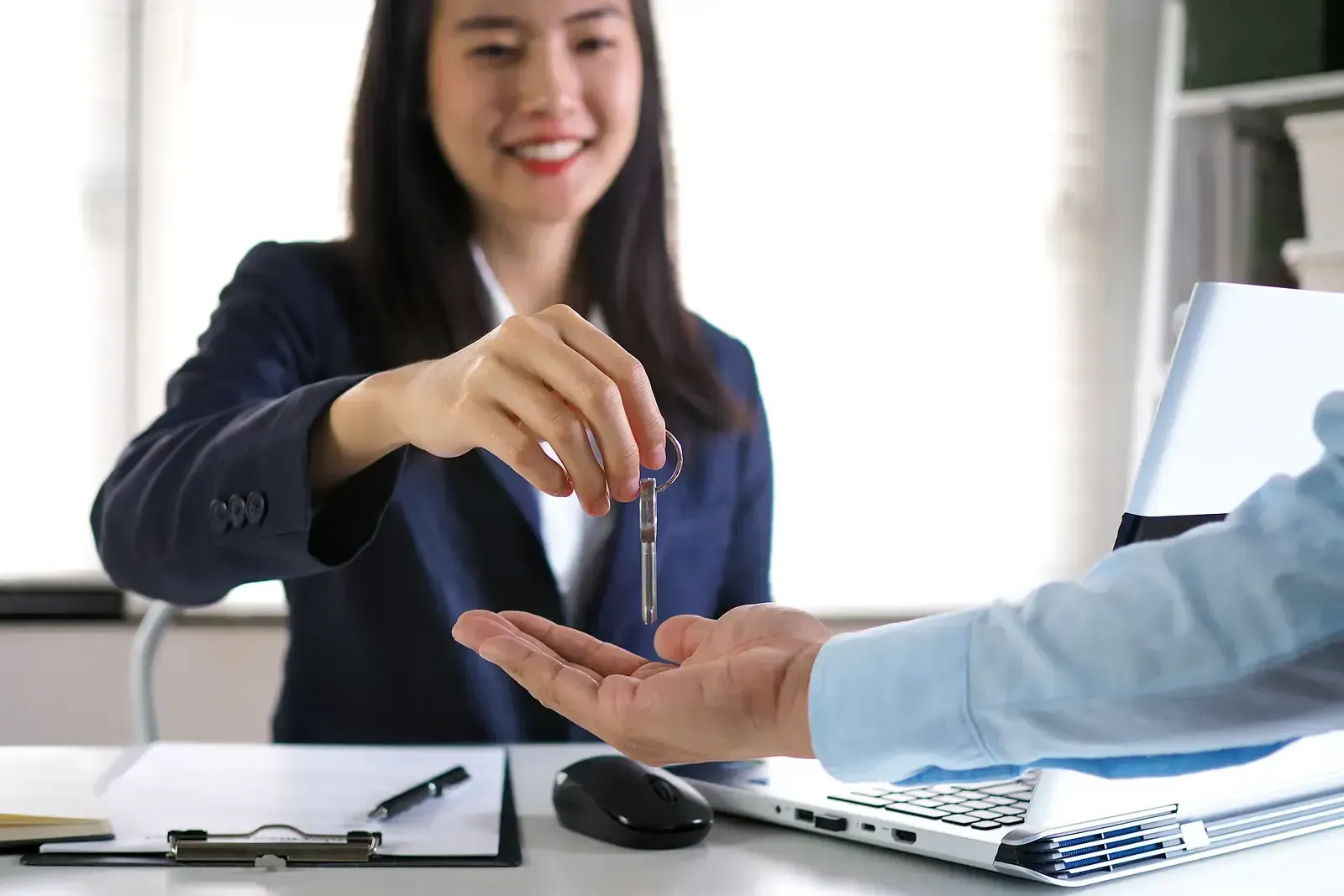 A tenant and a landlord shaking hands in front of a home.