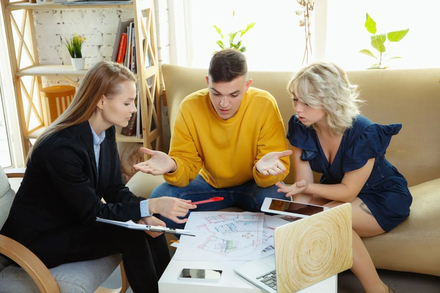 A woman in a suit consulting with a couple over paperwork at a table.